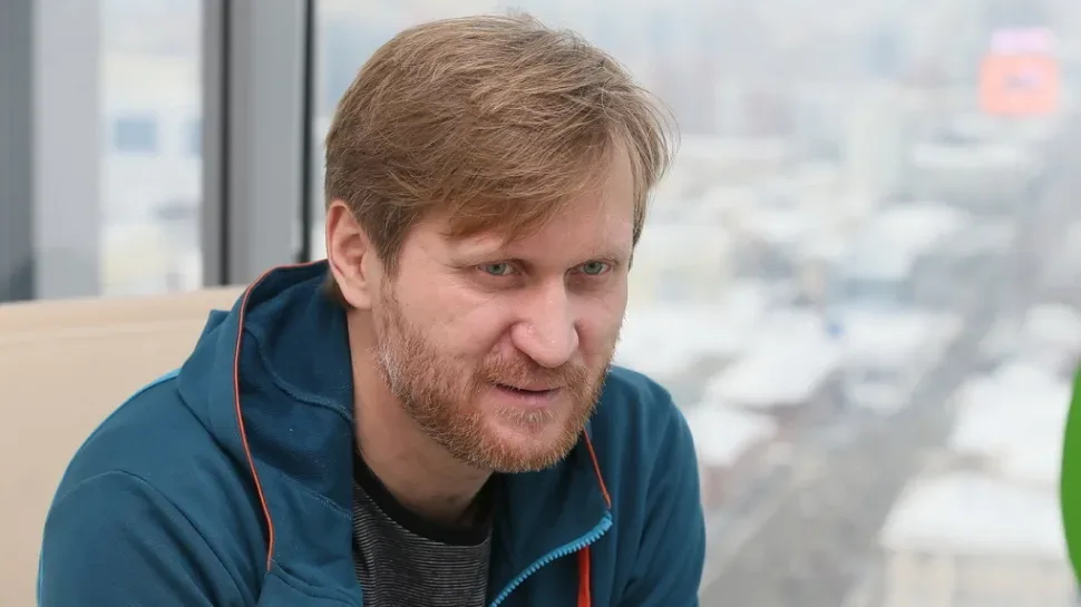 Мужчина с бородой в повседневной одежде у панорамного окна