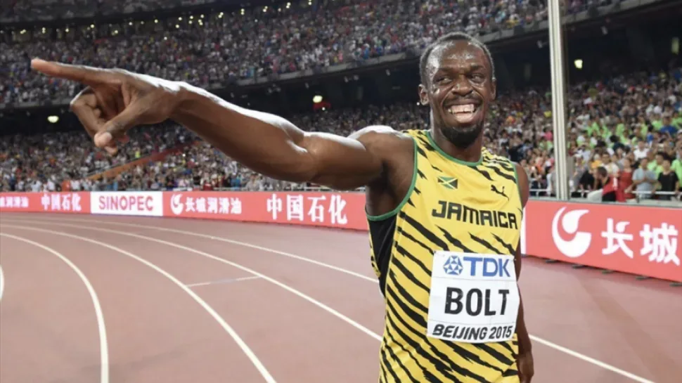 Улыбающийся ямайский спринтер в жёлто‑зелёной форме на треке у трибун