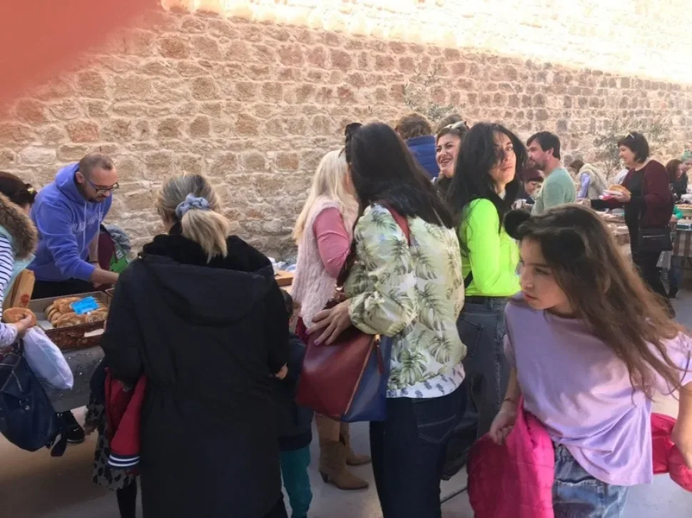 Толпа у столов с выпечкой и закусками в проходе комплекса