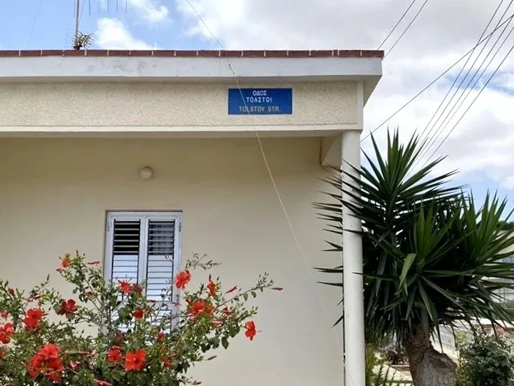 Дом с табличкой Tolstoy Str на улице Толстого и цветами
