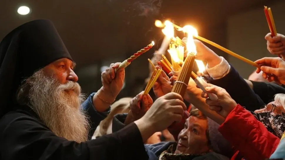 Иерарх и паломники зажигают свечи от Благодатного огня в Кувуклии Иерарх и паломники зажигают свечи от Благодатного огня в Кувуклии
