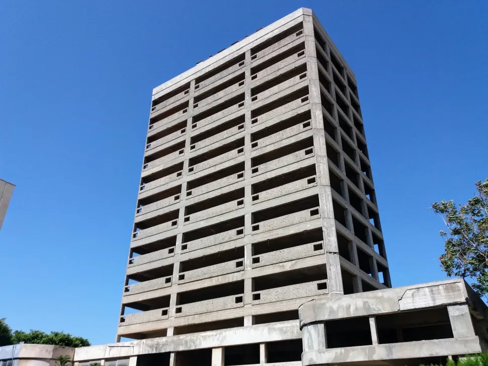 Уличный вид недостроенного MARITIME BUILDING с деревьями и припаркованными авто