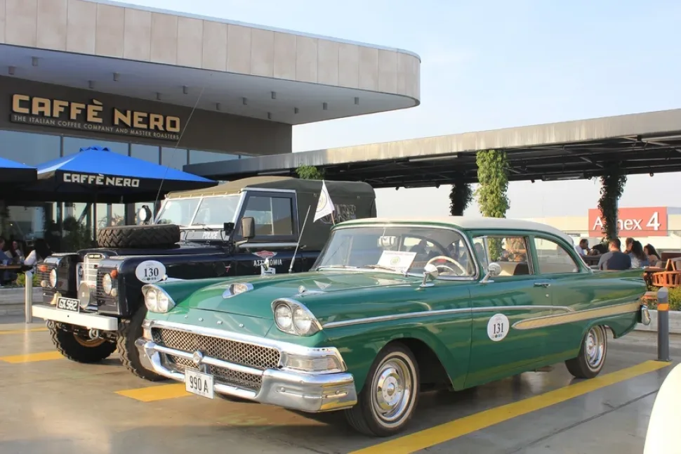 Чёрный внедорожник полиции и зелёный американский Cadillac в паре на выставке