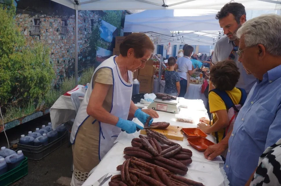 Продавщица нарезает традиционные мясные изделия на ярмарочном столе