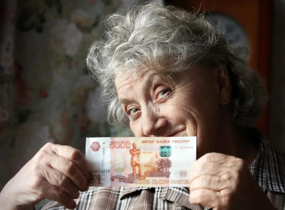 Пожилая женщина держит купюру 5000 рублей, тема нищей пенсии