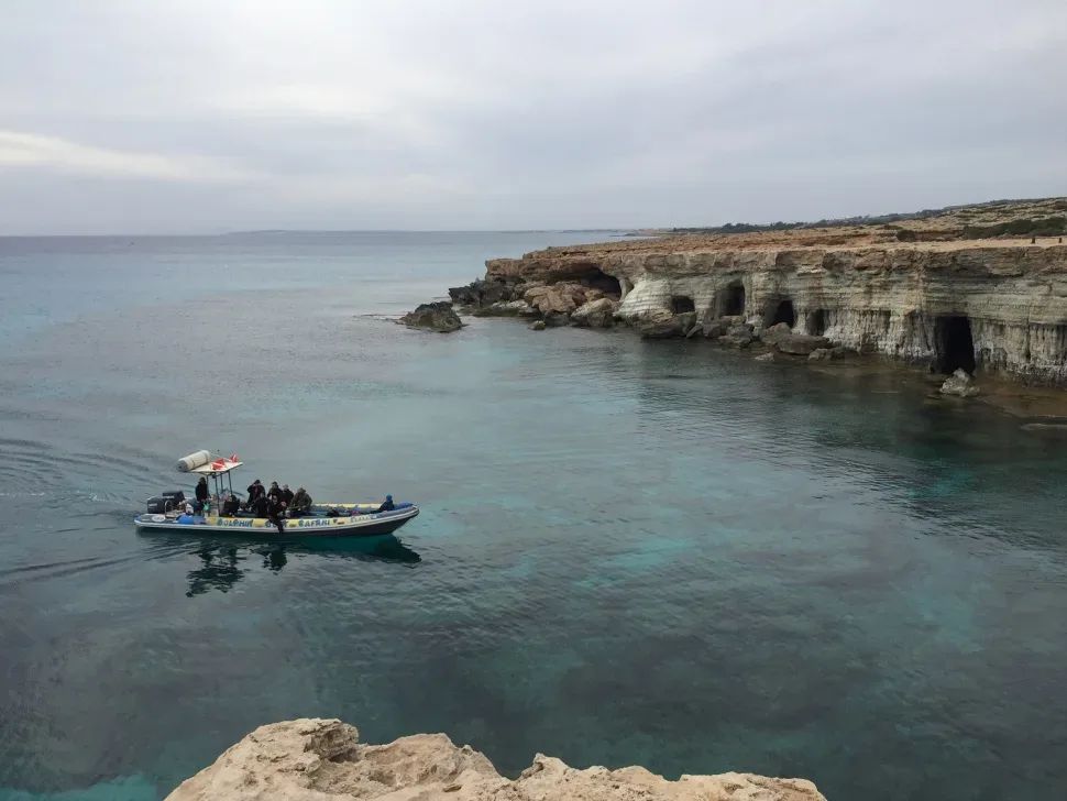 Надводная прогулочная лодка у прибрежных скал и пещер у моря