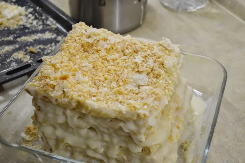 Собранный торт «Наполеон» с неровными краями перед обсыпкой крошками