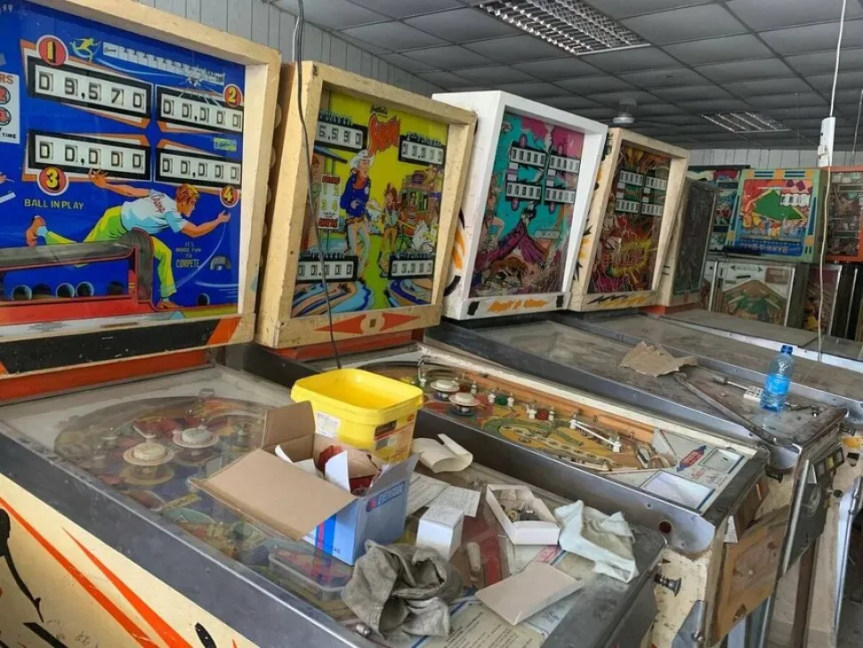Разнообразные игровые автоматы и пинболы у витрины склада