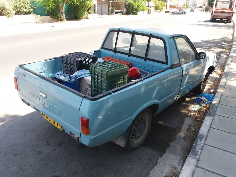 Светло‑голубой пикап с грузовыми ящиками в кузове на городской улице