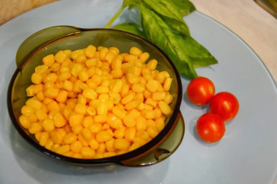 Чаша с консервированной кукурузой и помидорами черри для блюда