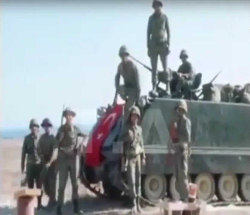 Сожжённый автомобиль на улице среди разрушений после боевых действий