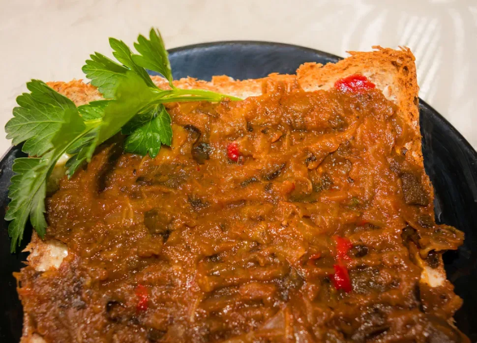 Верхний вид миски с баклажанной икрой, украшенной петрушкой и лимоном