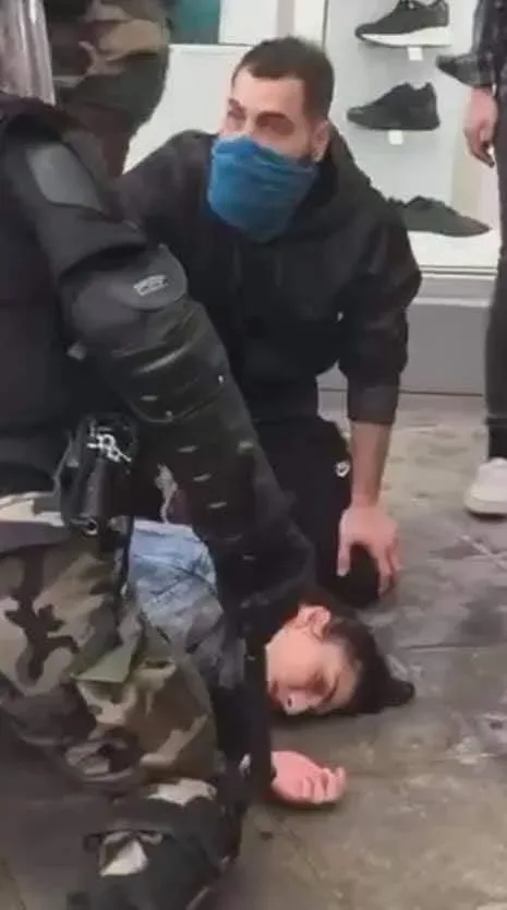 Полицейский задерживает лежащую пострадавшую у митинга в Никосии