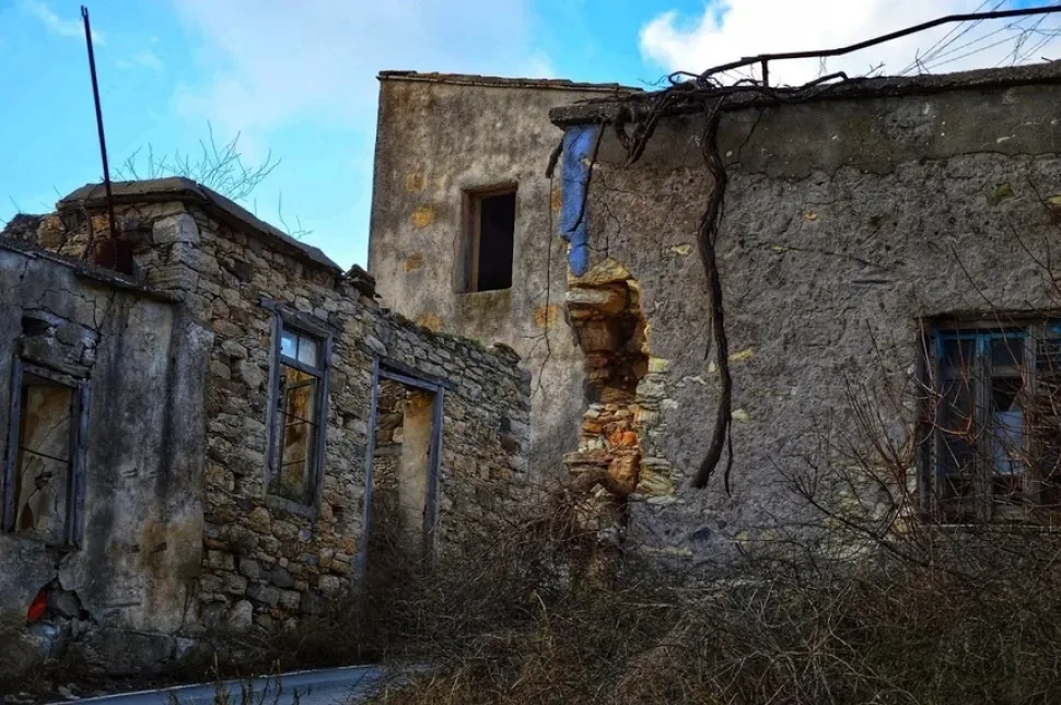 Старинный каменный дом Статос с черепичной крышей и зарослями