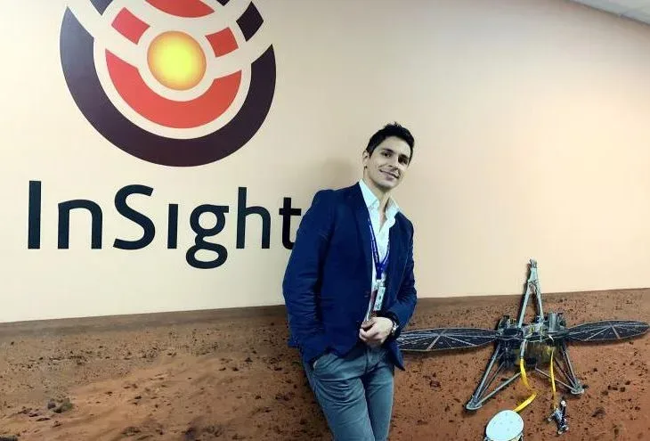 Молодой человек у стенда NASA InSight рядом с макетом марсохода
