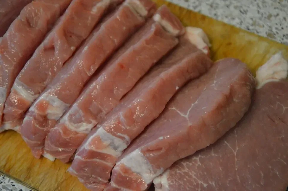 Нарезанный свиной карбонад тонкими кусочками на доске