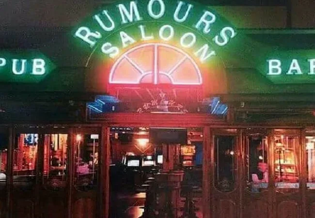 Вход в бар Rumours Saloon с яркой неоновой вывеской