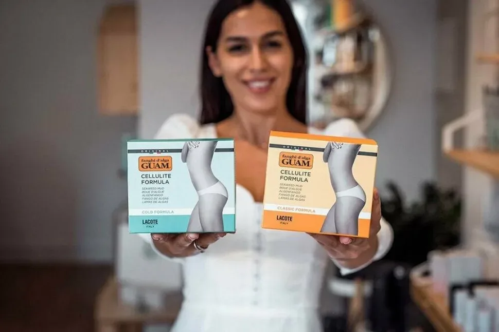 Продавец держит упаковки косметики GUAM в магазине ePharmaCY