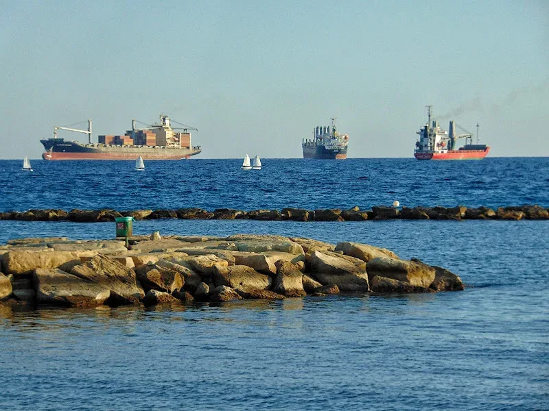 Морской вид с грузовыми судами на якоре и каменным волнорезом