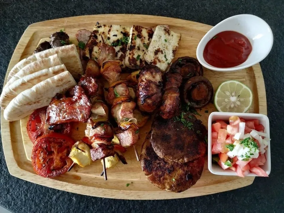 Мясное мезе из гриля с кебабами, халлуми и овощами на доске