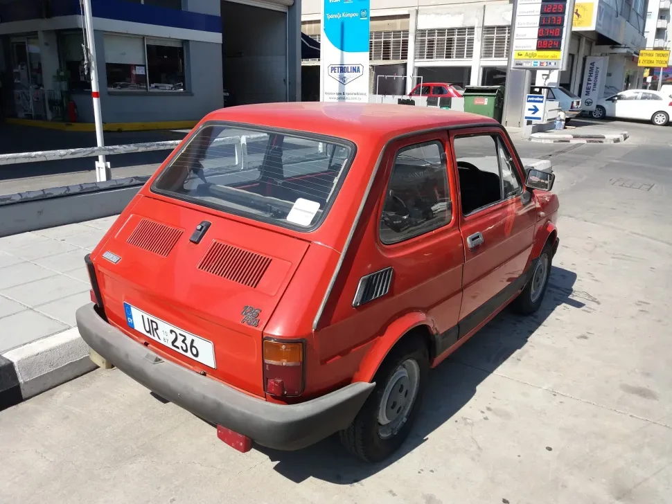 Красный польский Fiat 126l припаркованный у заправки