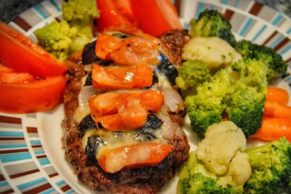 Отбивная с курагой и черносливом рядом с кусочками брокколи и томатом