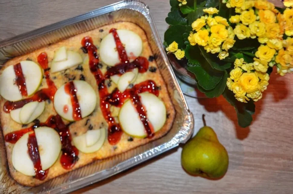 Порция творожной запеканки с дольками груши и виноградом на тарелке