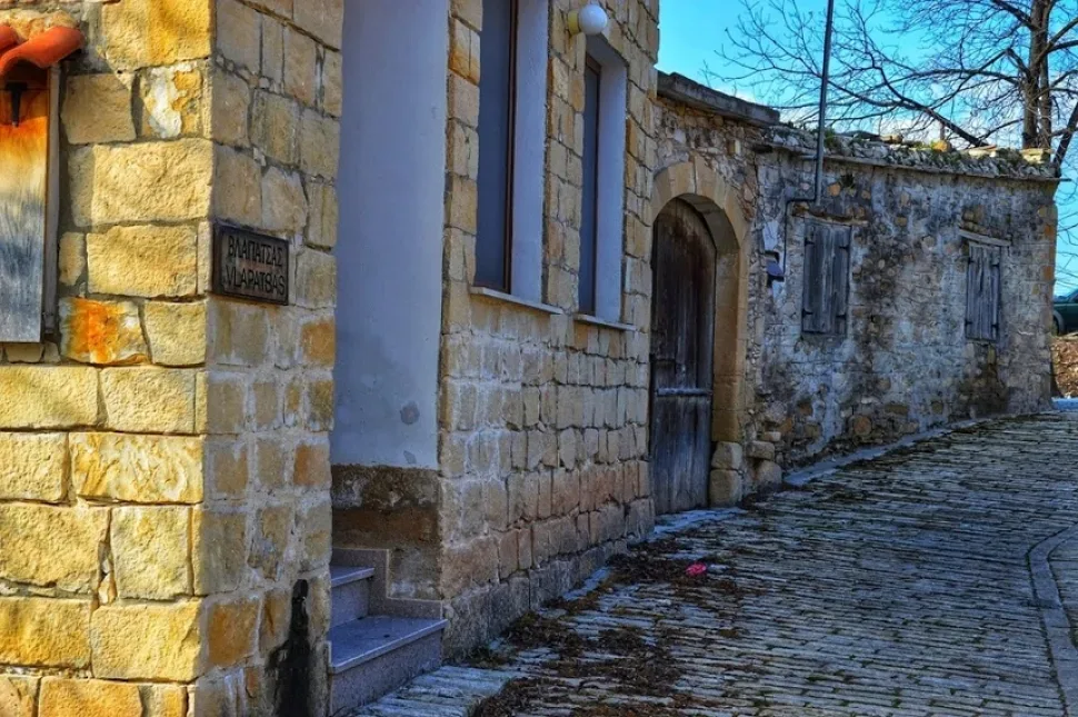 Пышный куст с жёлтыми цветами у каменной стены дома в Хулу