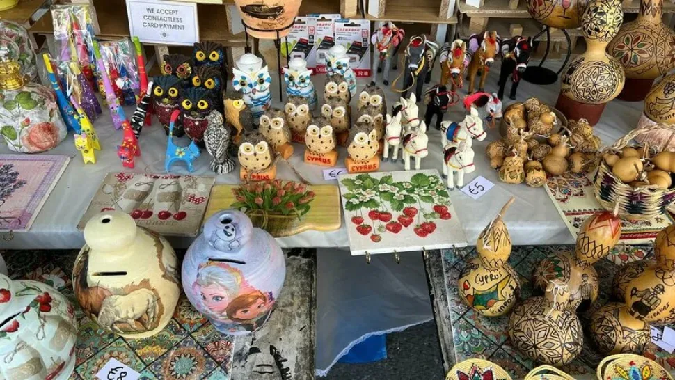 Разнообразные туристические сувениры и расписные поделки на столе ярмарки