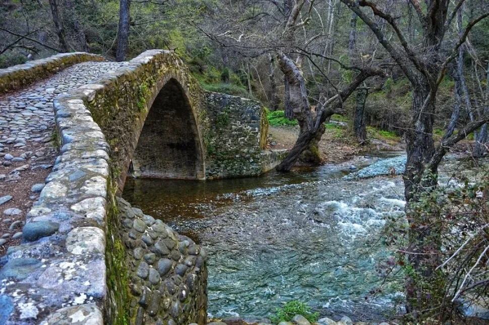 Каменный пролёт моста, склоны и прозрачная речная вода под ним