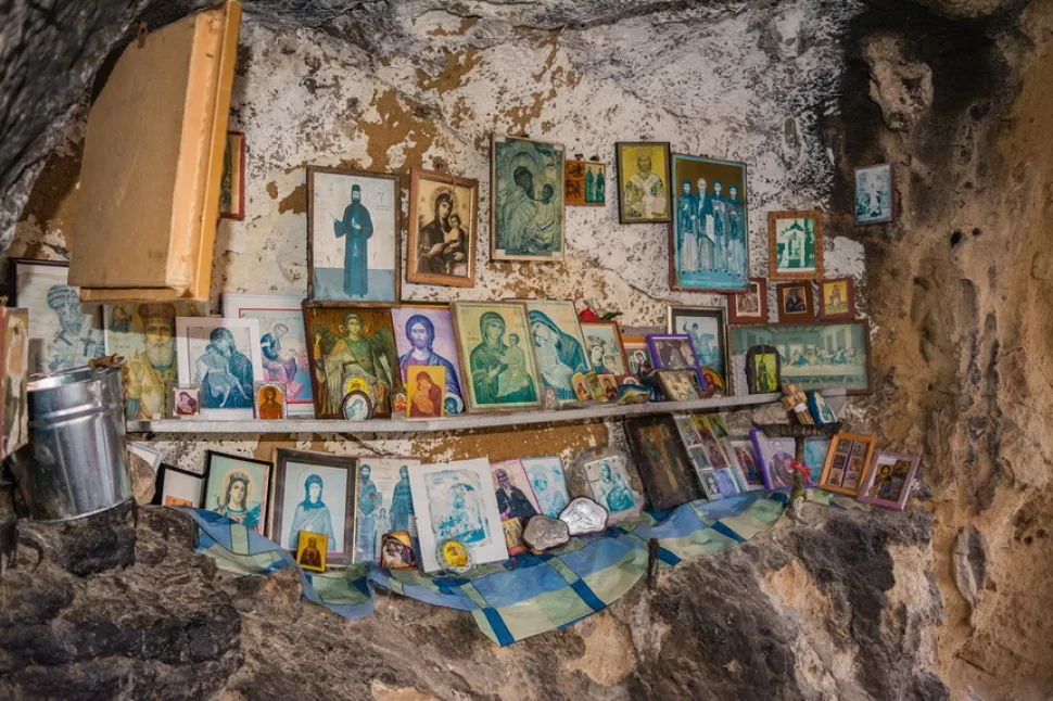 Стена пещеры украшена многочисленными иконами и подношениями