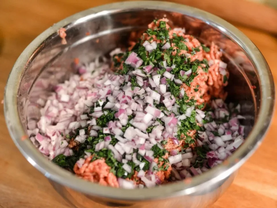 Миска со свиным фаршем, мелко нарезанным луком и петрушкой для шефтальи