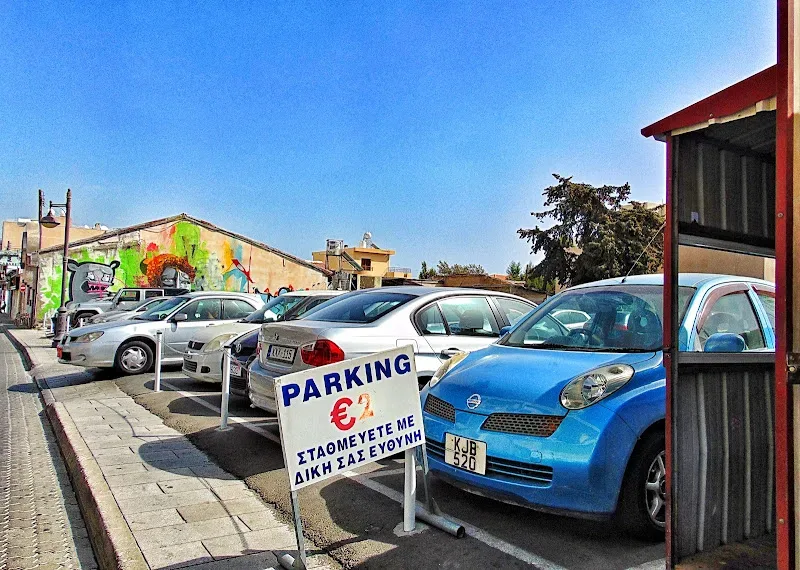 Уличная парковка с табличкой «PARKING €2» и припаркованными автомобилями