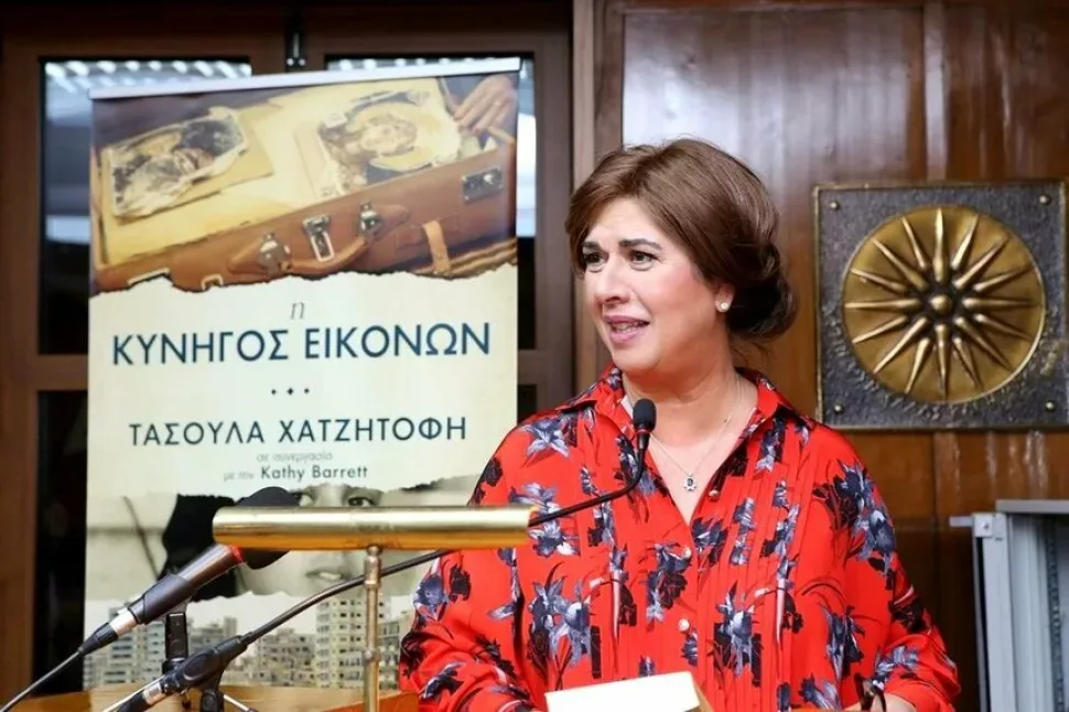 Женщина у микрофона на фоне постера её книги во время выступления Женщина у микрофона на фоне постера её книги во время выступления