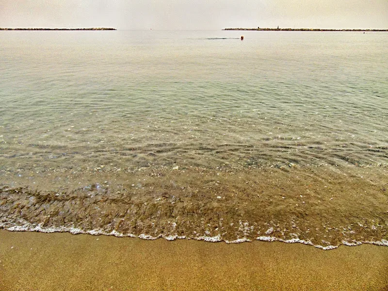 Женщина в купальнике стоит в тёплой воде моря на фоне пыльного неба