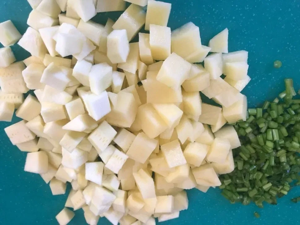 Нарезанная картофелина кубиками и порубленные стебли сельдерея