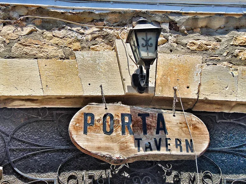Уличный фонарь над деревянной вывеской таверны Porta Tavern