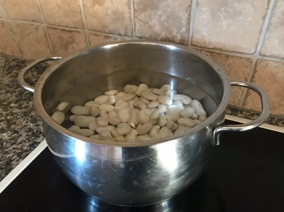 Кастрюля с белыми бобами в воде для варки бульона