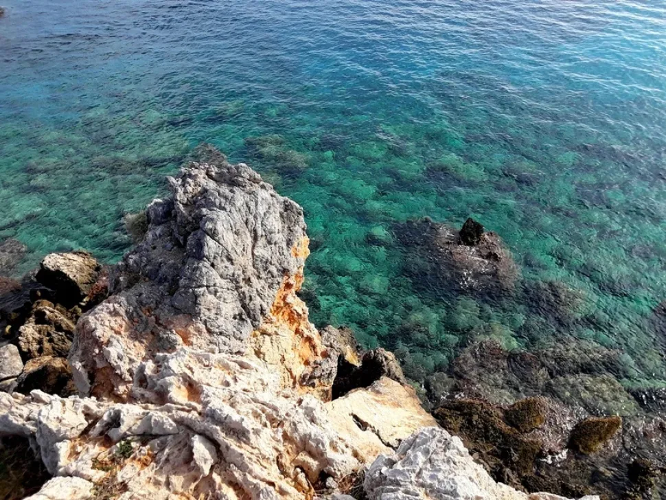 Крутые прибрежные скалы и бирюзовая вода в бухте на мысе Крутые прибрежные скалы и бирюзовая вода в бухте на мысе