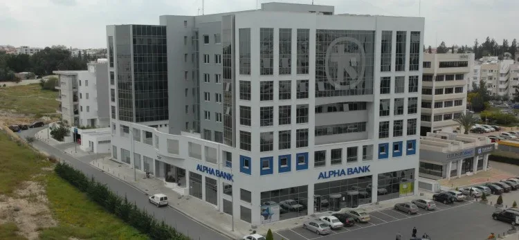 Здание отделения Alpha Bank на Кипре с парковкой и крупным логотипом