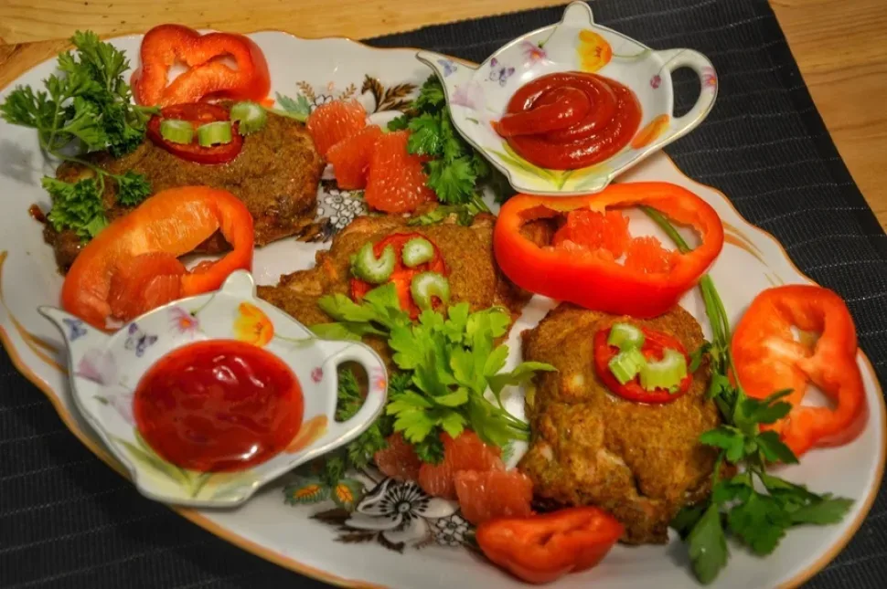 Запечённые кусочки курицы, украшенные зеленью и грейпфрутом