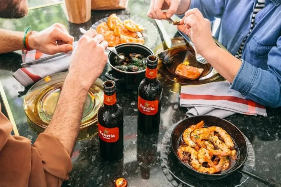 Гости дегустируют тапас за столом с бутылками Estrella Damm