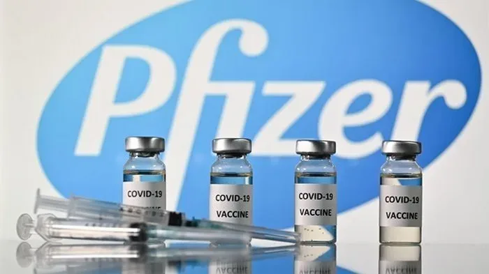 Флаконы вакцины Pfizer‑BioNTech Comirnaty и шприцы на фоне логотипа Pfizer Флаконы вакцины Pfizer‑BioNTech Comirnaty и шприцы на фоне логотипа Pfizer
