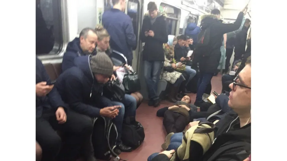 Пассажир метро спокойно лежит на полу вагона между сидящими людьми Пассажир метро спокойно лежит на полу вагона между сидящими людьми