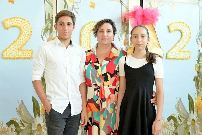 Женщина с двумя подростками на праздничном школьном фоне года