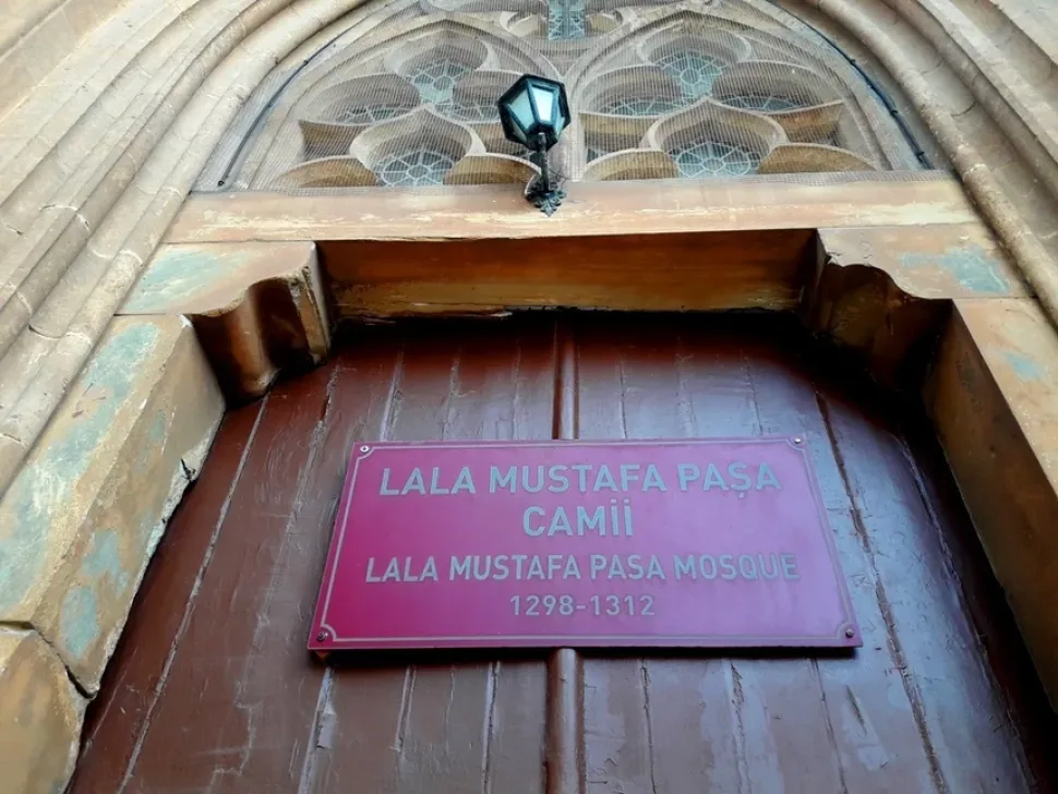 Дверь с табличкой Lala Mustafa Pasa Camii у входа в мечеть бывшего собора