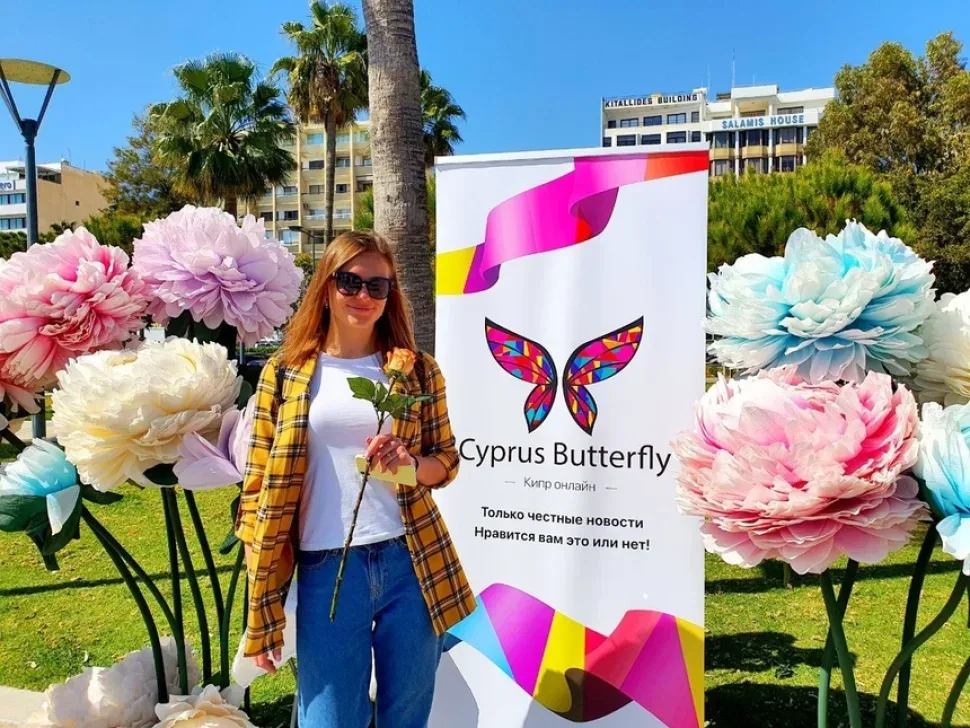 Женщина с дочерью у баннера Cyprus Butterfly держит розу после акции