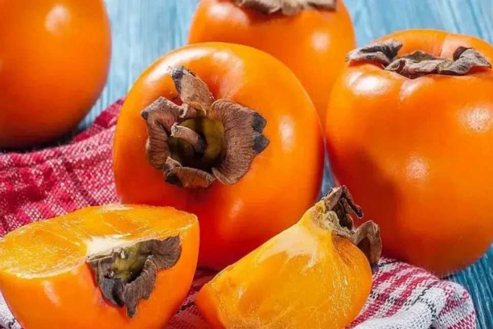 Спелая хурма целая и разрезанная дольками на ткани