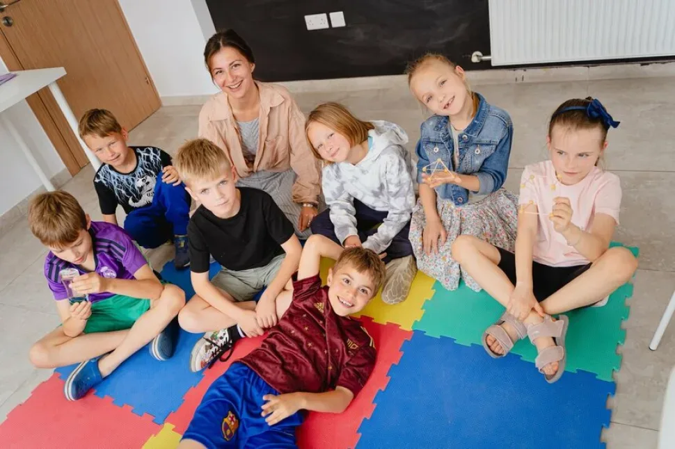 Дети с преподавателем в лагере Upstairs за занятиями на ярких ковриках Дети с преподавателем в лагере Upstairs за занятиями на ярких ковриках