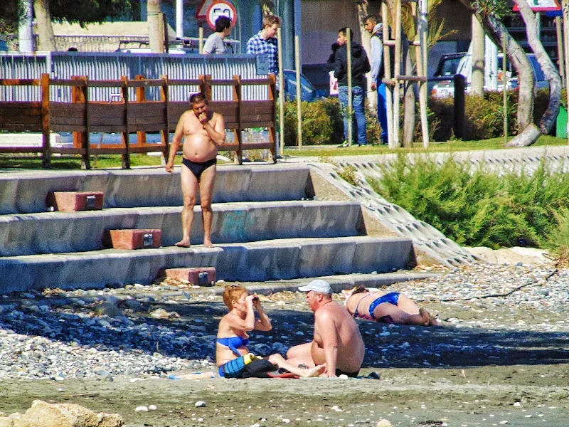 Несколько купающихся и загорающих на пустом каменистом пляже